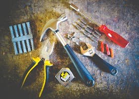 Collection of hand tools including hammer, screwdriver, and pliers in a workshop setting.